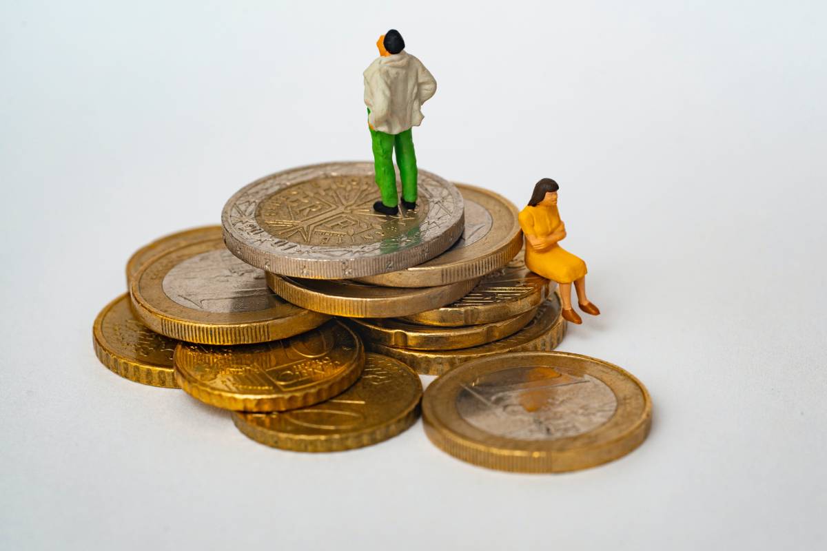 2 Mini-Figuren sitzen auf einigen Geldmünzen, den Blick voneinander abgewandt - Aufteilung des ehelichen Gebrauchsvermögens